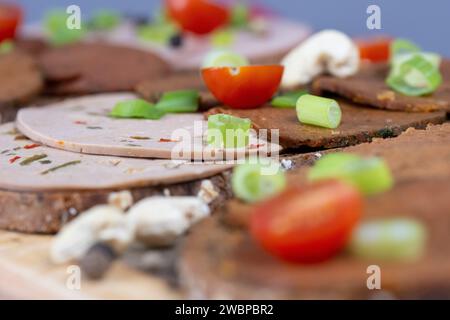 Dresden, Deutschland. Januar 2024. Brotscheiben mit verschiedenen veganen Würstchen liegen auf einem Holzbrett. Sie sind verzehrfertig, attraktiv verpackt und enthalten oft viel Zucker, Salz, Fett und Zusatzstoffe, aber nur wenige wichtige Nährstoffe. Stark verarbeitete Lebensmittel landen sehr oft im Warenkorb. Experten sehen Risiken im Zusammenhang mit hohem Konsum (dpa 'oft serviert, selten gesund: Hochprozessierte Lebensmittel') Credit: Sebastian Kahnert/dpa/Alamy Live News Stockfoto