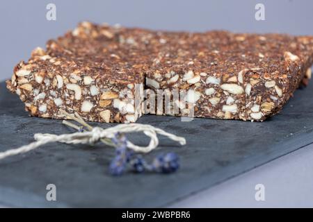 Dresden, Deutschland. Januar 2024. Cashew-Dattelstangen liegen auf einem Schneidebrett. Sie sind verzehrfertig, attraktiv verpackt - oft enthalten sie viel Zucker, Salz, Fett und Zusatzstoffe, aber wenig wichtige Nährstoffe. Stark verarbeitete Lebensmittel landen sehr oft im Warenkorb. Experten sehen Risiken im Zusammenhang mit hohem Konsum (dpa 'oft serviert, selten gesund: Hochprozessierte Lebensmittel') Credit: Sebastian Kahnert/dpa/Alamy Live News Stockfoto