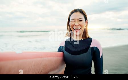 Frau, Porträt und Lachen für Surfen am Strand, Meer und Meer im Sommerurlaub, Reise Abenteuer oder Spaß. Glücklicher japanischer Surfer mit Board für Stockfoto