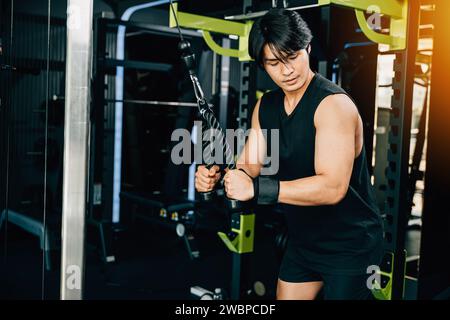 Junger Mann, der Seiltrizeps-Pulldowns durchführt, um Muskeln und Kraft aufzubauen Stockfoto