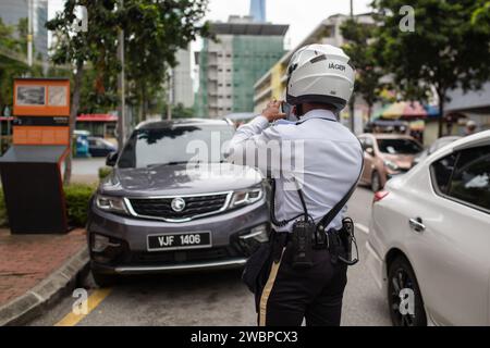 Kuala Lumpur, Malaysia - 8. Januar 2024: Verkehrspolizist fotografiert und stellt Fahrkarten für Besitzer illegal geparkter Fahrzeuge aus. Stockfoto