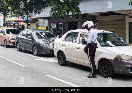 Kuala Lumpur, Malaysia - 8. Januar 2024: Verkehrspolizist fotografiert und stellt Fahrkarten für Besitzer illegal geparkter Fahrzeuge aus. Stockfoto