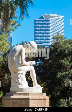 Junge, der Thorn (Marmor) Statue in den Royal Botanic Gardens, Sydney, Australien herauszieht. Eine Kopie des Spinario importierte 1883. AMP-Quartal im Hintergrund Stockfoto