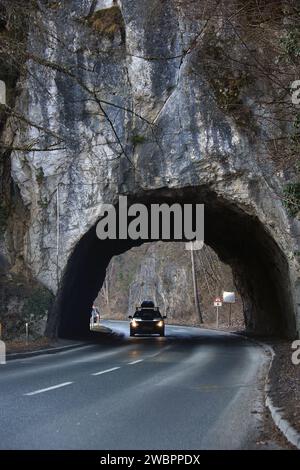 Ein Auto mit Scheinwerfern fährt durch einen kleinen Tunnel. Stockfoto