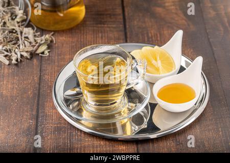 Getrockneter Salbeitee in Glasbecher auf Holztisch Stockfoto