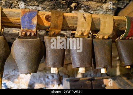 Hängende Kuhschafglocke mit Lederarmband, die in einem alten rustikalen Objekt der Scheune hängt Stockfoto