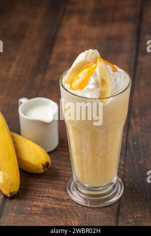 Bananen-Smoothie in Glasbecher auf Holztisch Stockfoto