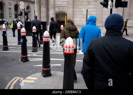 Stadtarbeiter gehen an neuen Straßenpfollern vorbei, nachdem sie am 11. Januar 2024 in London, dem Finanzviertel der Hauptstadt, die Threadneedle Street gegenüber der Bank of England verbreitert haben. Stockfoto
