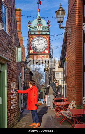 Frau, die eine Postkarte aus einer Auswahl an der Wand eines Ladens an den römischen Wänden bei der Eastgate-Uhr in Cheshire in Chester, England, auswählt Stockfoto