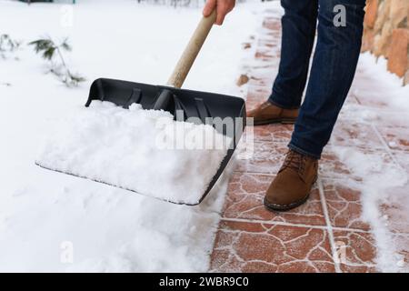 Ein Mann entfernt Schnee mit einer Schaufel vom Weg in der Nähe des Hauses Stockfoto