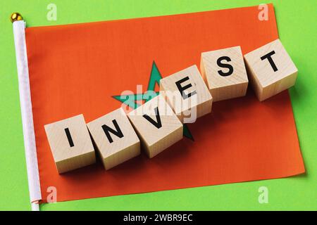 Holzwürfel mit Text und Fahne auf farbigem Hintergrund, ein Konzept zum Thema Investition in Marokko Stockfoto