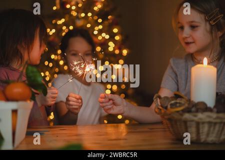 Drei kleine Mädchen feiern weihnachten zu Hause, Sparkler, Mandarinen. Stockfoto