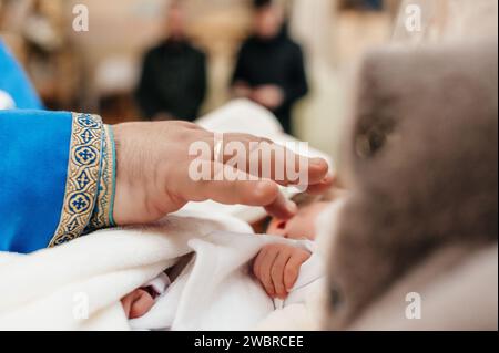 Der Priester führt den Ritus der Taufe des Kindes aus und salbt das Bein mit heiliger Myrrhe, dem Sakrament der christlichen Taufe. Stockfoto