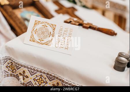 Eine Kindertaufe und kleine silberne Gläser mit Frieden, auf deren Hintergrund sich ein Kreuz befindet, Elemente kirchlicher Rituale. Stockfoto