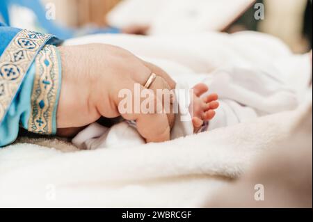 Der Priester führt den Ritus der Taufe des Kindes aus und salbt das Bein mit heiliger Myrrhe, dem Sakrament der christlichen Taufe. Stockfoto