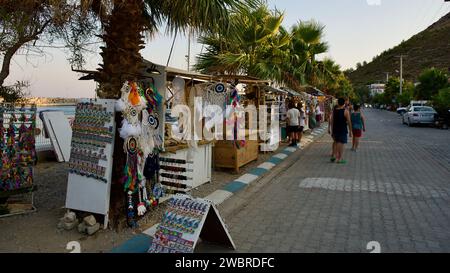 Ägäis und Mittelmeerküste bei Sonnenuntergang. Korbschirme und Sonnenliegen. Strandrestaurants. Palamutbuku Strände von Mugla, Turkiye. Stockfoto