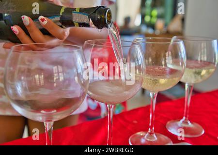 Frau, die während der Weihnachtszeit Prosecco-Sekt in Gläser gießt Stockfoto