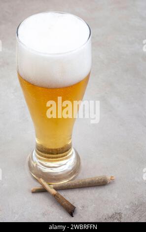 Marihuana-Gelenk mit Glas Bier auf grauer Grunge-Oberfläche Stockfoto