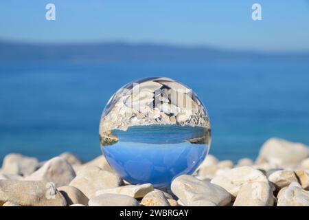 Glaskugel liegt auf Steinen am Strand, sonniger Herbsttag in Cres (Kroatien) Stockfoto