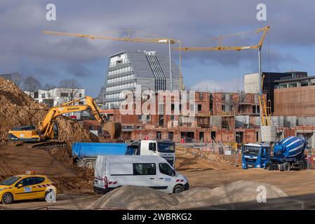 Selbstaufrichtende Krane Potain Hup 40-30 und IGO 50 auf einer Baustelle und einem Gebäude im Bau mit einem modernen Gebäude im Hintergrund. Stockfoto