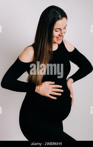 Elegante Erwartung: Ein Profil von Stärke und Gnade. Schwangere Frau im schwarzen engen Kleid. Wunderschöne Silhouette Stockfoto