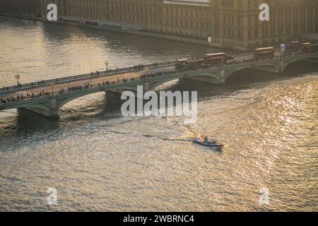 Blick auf London vom London Eye aus, mit einer Stadtlandschaft mit der Themse und einem Boot auf ihr sowie der London Bridge mit Autos. Stockfoto