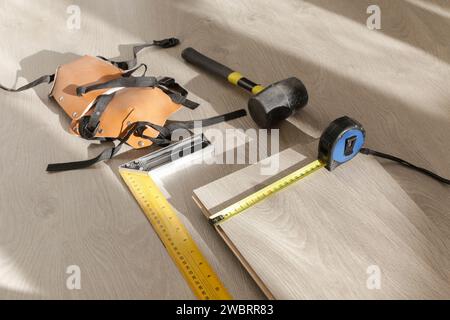 Gummihammer, Lineal mit Winkelstange, Bandmessgerät, Stichsäge und andere Werkzeuge für die Montage von Laminat-Vinylböden. Heimwerkerneuerung, neue Bodenmontage Stockfoto