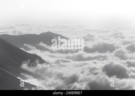 Nebel kriecht auf den Bergen hoch, in Schwarz-weiß. Stockfoto