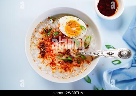 Hausgemachte asiatisch-chinesische Congee mit weich gekochten Ei, gebratenen Schalotten und Frühlingszwiebeln Stockfoto