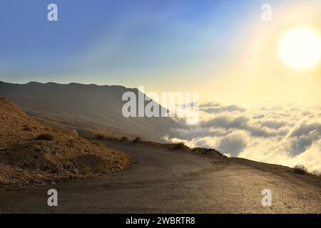 Nebel kriecht auf einer Bergstraße während Sonnenuntergang im Libanon. Stockfoto