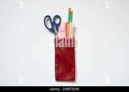 Schreibzubehör. Bleistift, Stift, Lineal, Textmarker, Schere in Bleistiftetui isoliert auf weißem Schreibtischhintergrund. Draufsicht Stockfoto