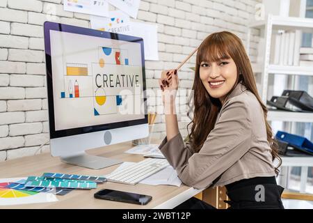 Eine junge asiatische Grafikdesignerin, die in einem kreativen dynamischen Büro arbeitet Stockfoto