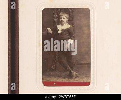 Porträt eines stehenden Jungen mit Reitpeitsche in der Hand, Willem Hooijer, 1878 - 1892 Foto. Visitenkarte dieses Foto ist Teil eines Albums. Haarlem Karton. Fotografischer Trägeralbumendruck historischer Personen. Junge (Kind zwischen Kleinkind und Jugend). Peitsche Stockfoto