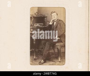 Porträt eines sitzenden jungen Mannes an einem Schreibtisch, genannt Jo, Anonym, 1860 - 1900 Foto. Visitenkarte dieses Foto ist Teil eines Albums. Niederlande Pappe. Fotografischer Trägeralbumendruck historischer Personen. Sitzende Figur. Jugend, Jugendliche. Schreibtisch, Schreibtisch Stockfoto