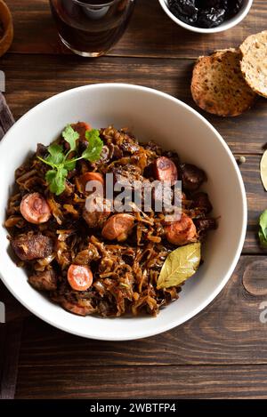 Polnische Bigos. Gedünsteter Kohl mit Sauerkraut, Pilzen, Räucherfleisch und Gewürzen in einer Schüssel auf Holztisch. Landhausstil, Nahansicht Stockfoto