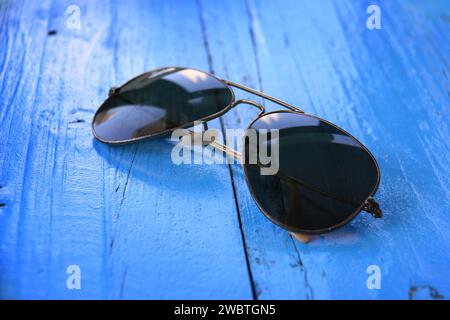 Eine Sonnenbrille auf einem blauen Holztisch. Stockfoto