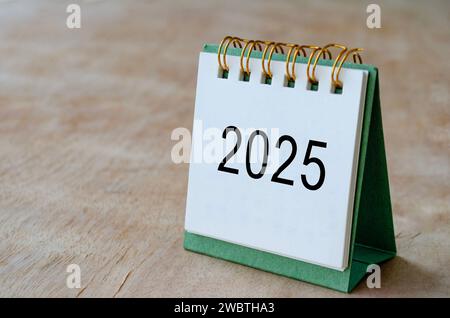 2025 Tischkalender auf Holzschreibtisch mit anpassbarem Platz für Text. Kopierbereich und Kalenderkonzept. Stockfoto