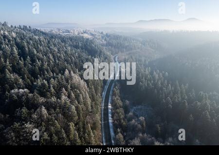 Eine Straße führt durch ein Waldstück mit Schnee bedeckten Nadel- und Laubbäumen bei Rottweil. Rottweil Baden-Württemberg Deutschland *** Eine Straße führt durch ein Waldgebiet mit schneebedeckten Nadelbäumen und Laubbäumen bei Rottweil Rottweil Baden Württemberg Deutschland Stockfoto