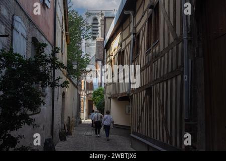 Besucher spazieren durch mittelalterliche Fachwerkhäuser und gehen auf dem breiteren Teil der ruelle des Chats, der schmalsten Straße in Troyes, Frankreich, nach Norden. Stockfoto