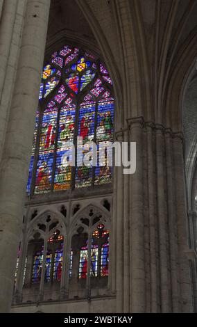 Farbenprächtige Buntglasfenster aus dem XIII. Jahrhundert im Kirchenschiff von St. Paul und St. Peter Kathedrale in Troyes, Frankreich, durch einen Steinbogen gesehen. Stockfoto