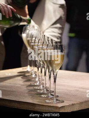 Champagner wird im Coopérative Chassenay d'Arce bei Troyes in eine Reihe von neun Gläsern gegossen. Stockfoto