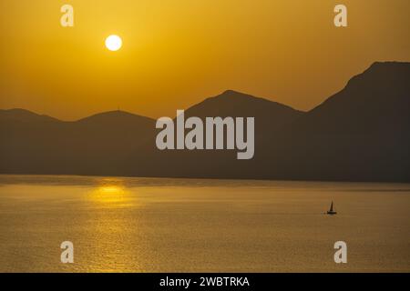 Sonnenaufgang hinter den Bergen des griechischen Festlandes von der Insel Meganisi im Ionischen Meer Stockfoto