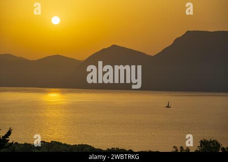 Sonnenaufgang hinter den Bergen des griechischen Festlandes von der Insel Meganisi im Ionischen Meer Stockfoto