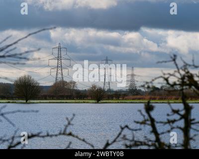 Strommasten und das überflutete Feld als Folge von starkem Regen in Oxfordshire, aufgenommen in Thrupp Turn, Faringdon - Konzept: Klimawandel Stockfoto