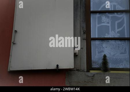 Ländliches Haus mit Holzläden, handgefertigten Vorhängen und einem Miniatur-Weihnachtsbaum in Rosheim, Elsass Frankreich. Stockfoto