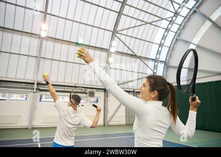 Der Manntrainer erklärt der Spielerin während des Tennisunterrichts die Serviertechnik Stockfoto