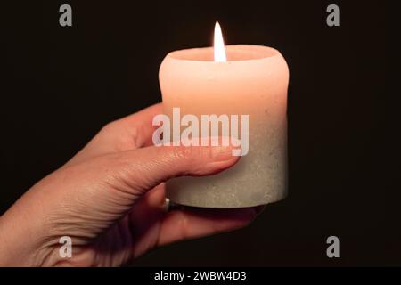 Eine Hand hält eine Kerze im Dunkeln Stockfoto