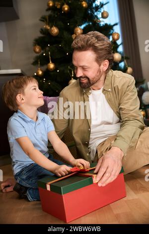 Vater und Sohn eröffneten Weihnachtsgeschenk-Box, um Silvester im Hotel zu feiern Stockfoto
