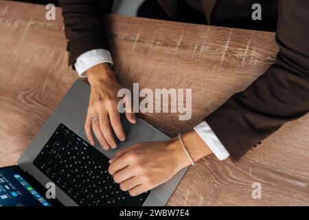 Hochwinkelansicht eines nicht erkennbaren Geschäftsmannes, der auf der Tastatur des Laptops schreibt, Informationen sucht, auf dem Schreibtisch im Internet surft, Entfernung Stockfoto
