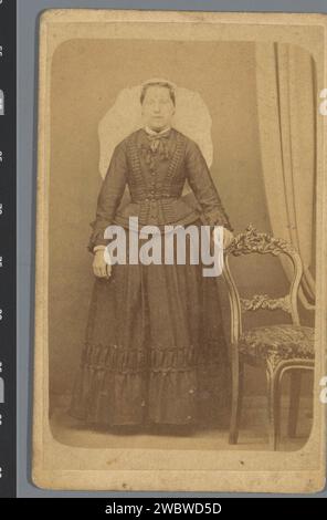 Porträt einer unbekannten Frau neben einem Stuhl, anonym, 1854 - 1885 Foto. Visitenkartenpapier. Pappalbumendruck Erwachsene Frau. Anonyme historische Person porträtiert Stockfoto